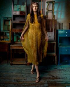 woman in yellow dress posing in front of old furniture